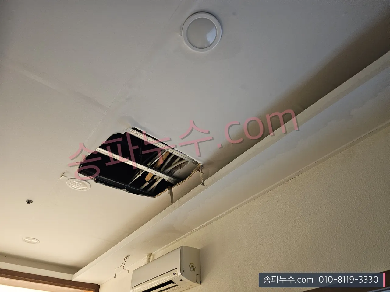 천장 점검구를 열어 상부 배관을 확인하는 모습