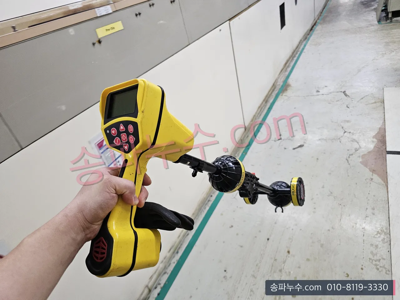 전자 탐지기로 바닥 아래 배관 경로를 따라가는 모습